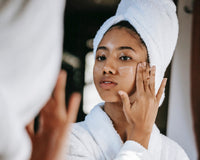 Young girl looks in mirror and moisturizes face